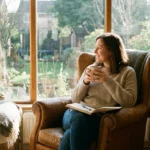 A person peacefully journaling by a sunny window with a cup of tea
