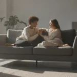 A loving couple sitting on a couch, holding hands in a reassuring and comforting manner.